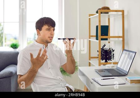 Young businessman using his mobile to talk on speaker phone or send voice messages Stock Photo