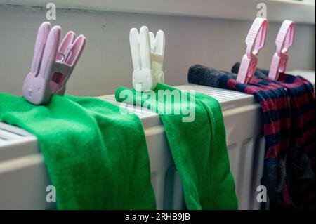 Two pairs of colored socks with clothespin on the white radiator after washing. Housing, economy, domestic theme Stock Photo