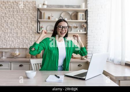 Portrait of a young business woman, a freelancer who rejoices at the finished successful project, looks at the camera and rejoices at the success. Stock Photo