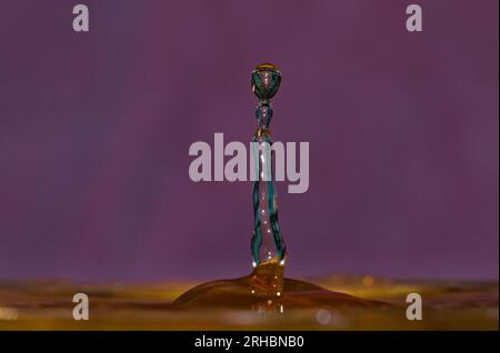 abstract photo of Water droplet impact isolated on colourful violet backround. fun with water Stock Photo