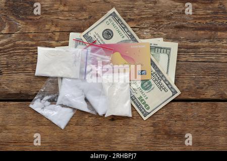 Plastic bags with drugs, credit card and money on wooden background Stock Photo