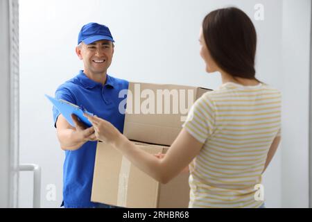 Young woman receiving parcels from courier in stairway Stock Photo