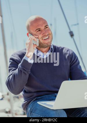 Stock photo of a businessman sitting with a computer in his legs and talking on the phone. Lifestyle Stock Photo