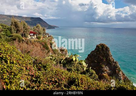 Turquoise gulf bay of Cape Capo Vaticano, Calabria, Southern Italy. Sandy beach, green mountains and plants, blue sky, white clouds, cliffs platform Stock Photo