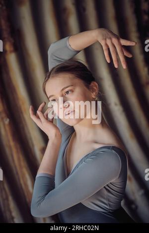 Attractive young female ballet dancer with raised arm looking into distance while gracefully dancing in old tunnel with shabby walls Stock Photo