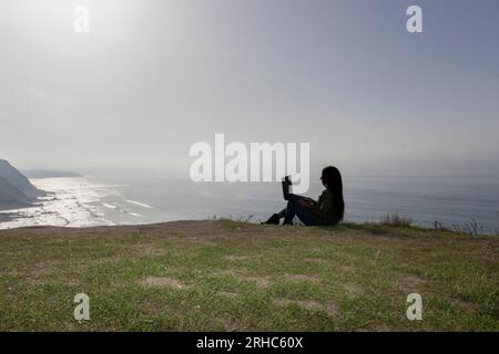 Stylish Woman Conducting a Video Conference Against an Ocean Backdrop Stock Photo