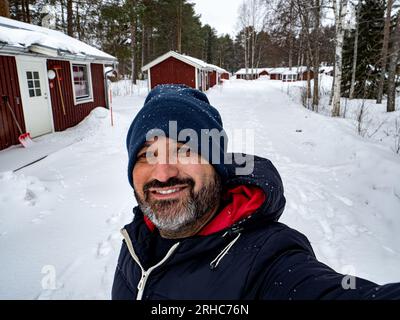 Pov of a man in winter clothes taking a smiling selfie in a snowy landscape in Sweden. Winter adventure traveler concept Stock Photo