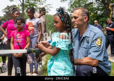 Detroit, Michigan - The Detroit Fire Department allows children to handle a fire hose as residents of the Morningside neighborhood hold a picnic/party Stock Photo