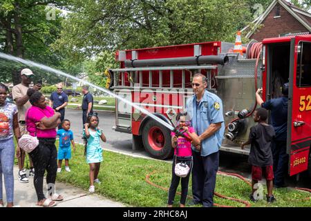 Detroit, Michigan - The Detroit Fire Department allows children to handle a fire hose as residents of the Morningside neighborhood hold a picnic/party Stock Photo