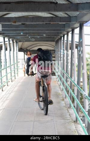 Salvador, Bahia, Brazil - August 11, 2023: A cyclist crossing the pedestrian walkway with his bicycle on Avenida Tancredo Neves in Salvador, Bahia, Stock Photo
