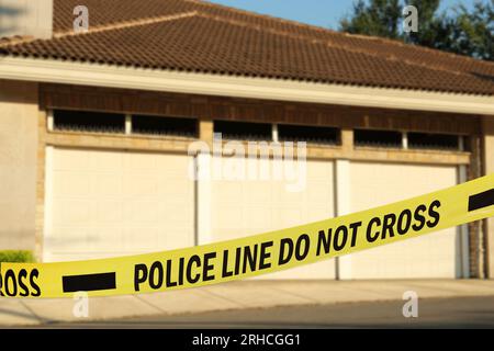 Yellow crime scene tape blocking way to garage outdoors Stock Photo