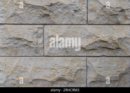 Stone wall - close up of grey blocks with yellow patches - horizontal pattern - uneven and rough surface Stock Photo