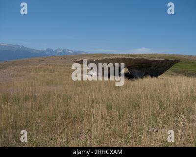 The Domo at Tippet Rise Art Center near Fishtail, Montana, with a field of dried grass in the foreground and the Beartooth Mountains in the background Stock Photo