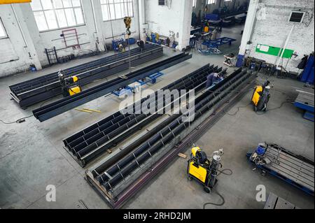 Long steel constructions assembling with welding in workshop Stock Photo