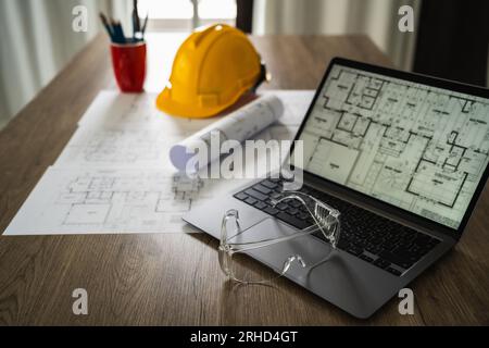 Architecture plans architect paper Clear protective glasses on a notebook computer discussing building plan design and blueprint paper Cropped image Stock Photo