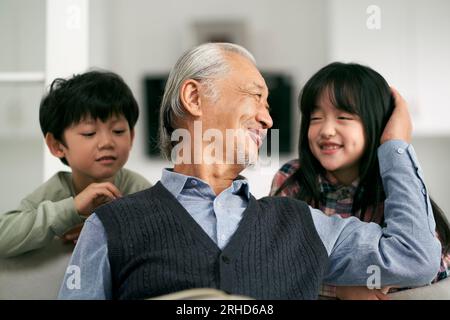 senior asian grandfather having a good time with two grandchildren at home Stock Photo