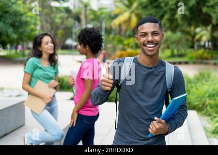 Successful african american male student with group of brazilian female young adults outdoor in tropical city Stock Photo
