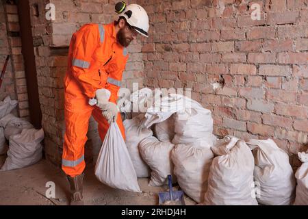 Construction worker transferring garbage in sugar bags on site manually. Stock Photo