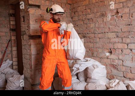 Construction worker transferring garbage in sugar bags on site manually. Stock Photo