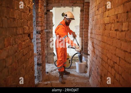 Constriction site worker cleaning brick wall with special vacuum cleaner. Stock Photo