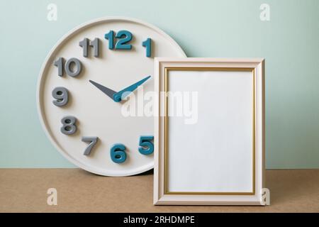Blank picture frame with clock on brown shelf. mint wall background. copy space Stock Photo
