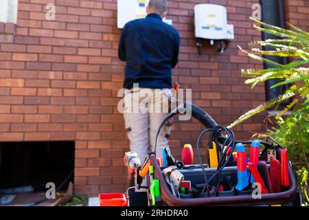 Electrical tradie working as an electrician doing a solar power installation on house Stock Photo