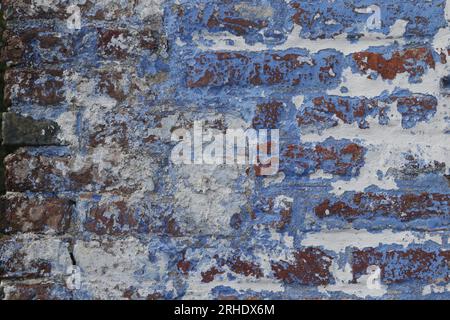 detail of old brick wall with peeled off blue and white paint Stock Photo
