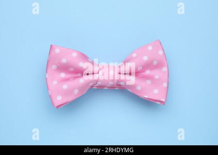 Stylish pink bow tie with polka dot pattern on light blue background, top view Stock Photo