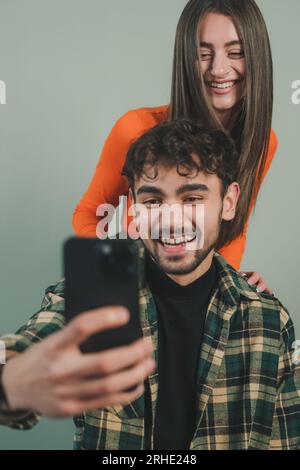 Man and woman bloggers having fun, recording online video clip using mobile phone isolated over green background. Social Media. Technology and Stock Photo