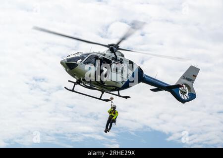 Aschau Im Chiemgau, Germany. 16th Aug, 2023. A police helicopter demonstrates the abseiling of a person during an air rescue exercise on the Kampenwand. Herrmann, (CSU) State Minister of the Interior, for Sport and Integration, informed himself at the appointment on the topics: alpine accident statistics, 'Safe mountain biking' and 'Safety equipment for via ferrata'. Also the demonstration of a mountain rescue with a helicopter, which is indispensable as a means of operation in the Bavarian mountains, was shown. Credit: Peter Kneffel/dpa/Alamy Live News Stock Photo