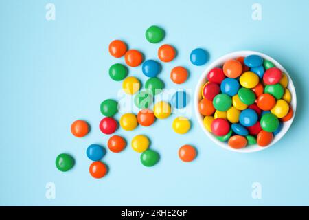 Vessel with Color Candies on blue background close-up Stock Photo