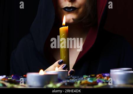 Witch hands performing a magic ritual holding a candle on a magical altar. Sorcerer rite of witchcraft and occultism. Halloween occult, esoteric and d Stock Photo