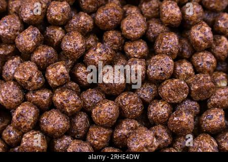 Brown chocolate breakfast balls cereal texture close up top view. Stock Photo