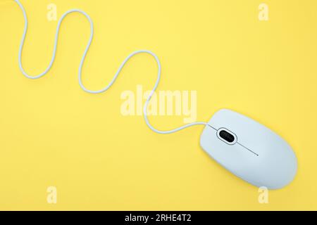 White modern wired computer mouse on yellow background. Computer technology concept Stock Photo