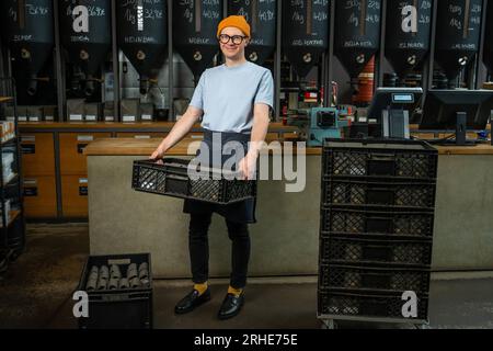Male worker or business owner uploads packages of coffee on factory or warehouse. Stock Photo