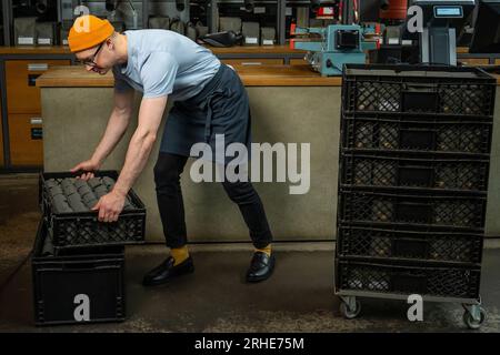 Male worker or business owner uploads packages of coffee on factory or warehouse. Stock Photo