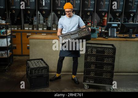 Male worker or business owner uploads packages of coffee on factory or warehouse. Stock Photo