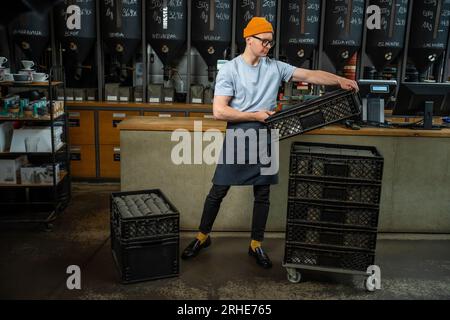 Male worker or business owner uploads packages of coffee on factory or warehouse. Stock Photo