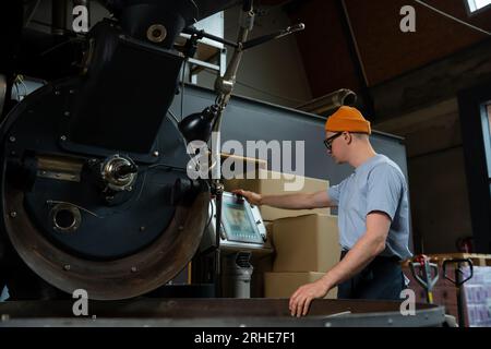 Roasting factory man worker operating process of creating coffee. Stock Photo