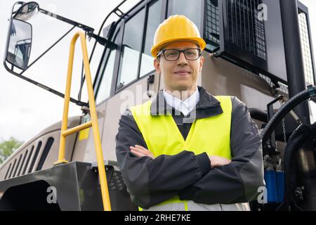 Engineer with tablet computer stands on the stairs to the cab of a truck Stock Photo