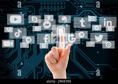 Woman hand pushing virtual social media icon on the circuit background, choice of social media concept Stock Photo