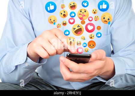 Businessman uses smart phone with virtual facebook emojis, social media reactions conept close-up Stock Photo