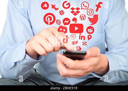 Businessman uses smart phone with virtual red social media apps icons, social media conept close-up Stock Photo