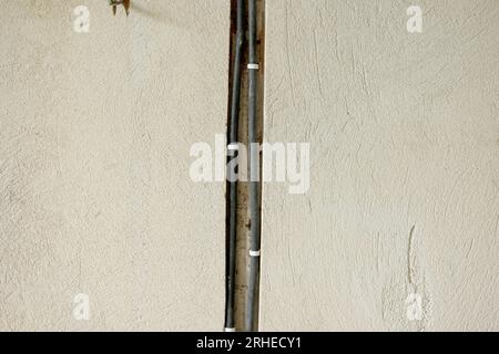 Wiring electrical cables on building concrete wall. Unfinished room with electricity wires, plaster wall in new apartment. Construction of house and h Stock Photo