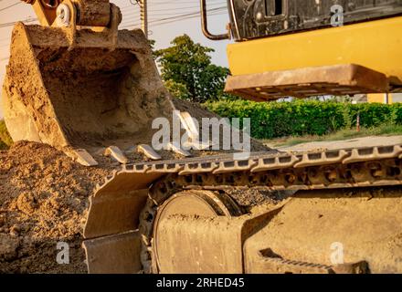 Backhoe parked at construction site after digging soil. Closeup bucket of bulldozer. Digger after work. Earth moving machine at construction site Stock Photo