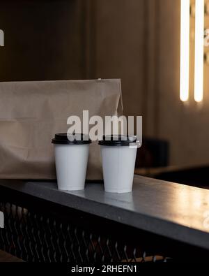two cups of coffee with carton bag, take away food, delivery coffee to go, on concrete table warm background, mexico latin america Stock Photo