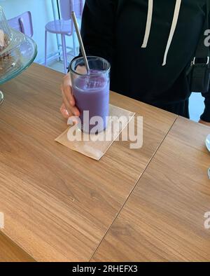 cold refreshing purple blackberry drink, on wooden table, latino man holding glass Stock Photo