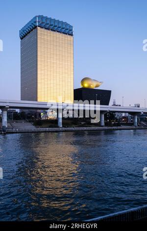 View of The Asahi Beer Hall (a.k.a. Super Dry Hall, or Flamme d'Or), seen from Asakusa, across the Sumida River, Tokyo, Japan, at twilight. Stock Photo