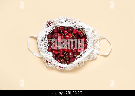 Mesh bag with fresh cherry on beige background Stock Photo