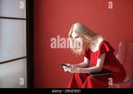 Young adult woman using smartphone and holding laptop Stock Photo